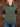 Person wearing a green sweater over a denim shirt with a wooden door background