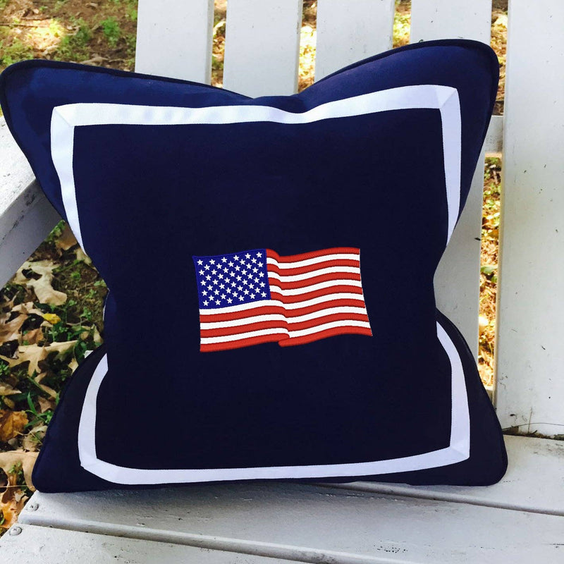 Navy blue pillow with American flag design on a white wooden surface