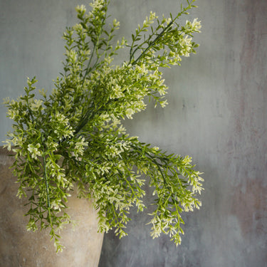 Green artificial plant in a pot against a gray wall