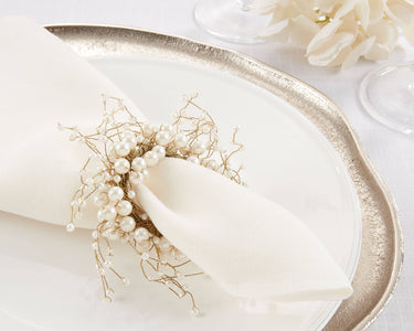 Decorative napkin with pearl embellishments on a white tablecloth.