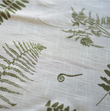 White cotton table runner iwth fronds printed on it
