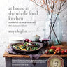Rustic farm table with a wooden bowl and harvest salad, fresh vegetables.  A large vase with natural branches with orange berries. Glassware and silverware accompanies linens. James Beard Award Winner badge. 
