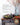 Rustic farm table with a wooden bowl and harvest salad, fresh vegetables.  A large vase with natural branches with orange berries. Glassware and silverware accompanies linens. James Beard Award Winner badge. 
