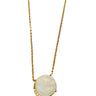 A gold chain necklace with a round white moonstone pendant set in a gold bezel with small clear accent stones, displayed on a textured taupe fabric background.