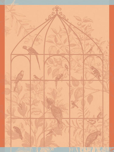Sonate Tea Towel Collection Shown in Orange colorway. Towel features several exotic birds sitting on an outline of a large aviary. The background is vegetation with leaves, flowers and fruit.